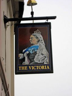 a sign hanging from the side of a building with a bell on it's side