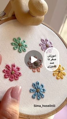 someone is holding a cross stitch project with flowers on it