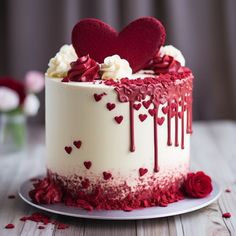 a white cake with red icing and hearts on top is sitting on a table