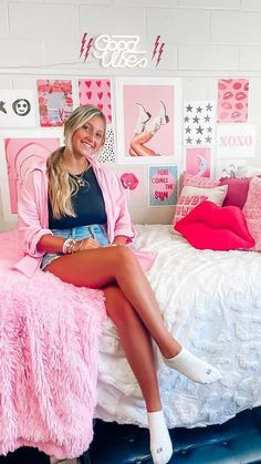 a woman sitting on top of a bed in a room filled with pink furniture and decor