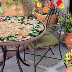 a mosaic table and chairs with potted plants in the background