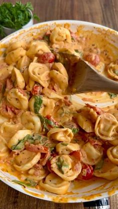 a bowl filled with tortellini shells covered in tomato sauce and garnished with parsley