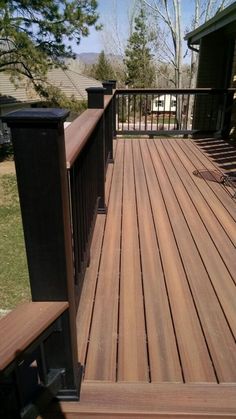 a wooden deck with metal railings in front of a house