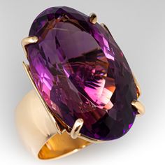 This well designed vintage cocktail ring features one (1) oval cut amethyst set with four prongs. The stone flashes a pinkish-orange when viewed from the side. The ring measures 26.3mm at the top, rises 14.9mm above the finger, tapering to 9.4mm wide and 1.6mm thick at the base of the shank.  It is currently a size 5.75. Amethyst Cocktail Ring, Pinkish Orange, Amethyst Set, Vintage Cocktail Ring, Eternity Band Ring, Vintage Cocktail, Amethyst Ring, Cocktail Ring, Eternity Bands