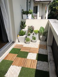 an outdoor patio with artificial grass and potted plants on the side of the house