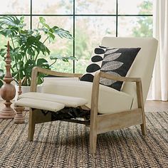 a living room scene with focus on the reclining chair and potted plant in the background