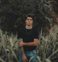 a man standing in the middle of a corn field with his arms crossed and looking off into the distance