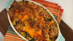 a casserole dish with meat and vegetables in it on a striped place mat