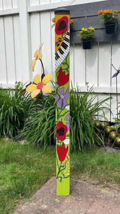 a tall wooden pole with flowers painted on it's side in front of a white fence