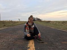 a woman sitting on the side of a road with her foot in the middle of the road