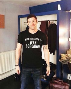 a man standing in front of a mirror wearing a t - shirt that says who the fock is west borland?