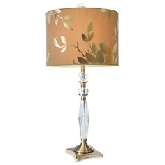 a table lamp with a gold shade on it and leaves painted on the lampshade