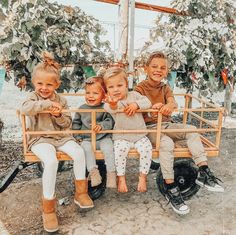 three children are sitting on a wooden bench