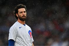 a baseball player standing in the rain with his head turned to look like he is wearing a chicago cubs uniform