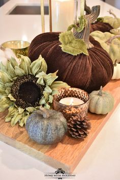 a wooden tray topped with pumpkins and sunflowers on top of a counter