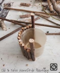 a cup filled with liquid sitting on top of a table next to sticks and branches