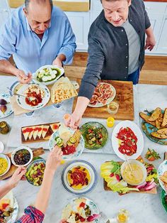 several people are gathered around a table with food on it and plates in front of them