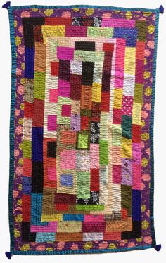 a multicolored patchwork quilt hanging on a wall