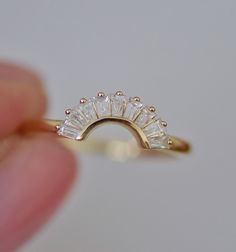 a close up of a person's hand holding a gold ring with three stones