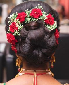 the back of a woman's head with red flowers in her hair and braid