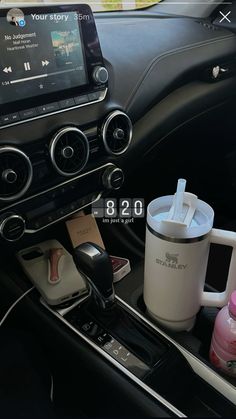 the interior of a car with various items in it, including a coffee cup and mp3 player