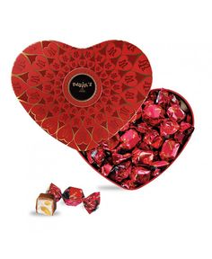 a heart shaped box filled with chocolates next to two pieces of candy in it