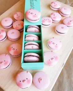 some pink macaroons are in a blue box on a table with other macaroons