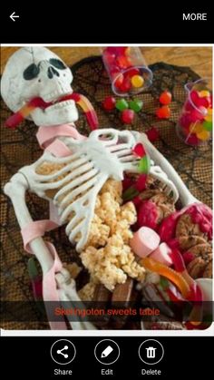 the skeleton is sitting on top of a table full of candy and candies,