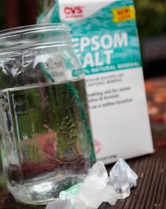 a glass jar filled with water and ice cubes next to a carton of epsom salt