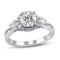 a diamond ring with three stones on the band and an oval center stone surrounded by small diamonds