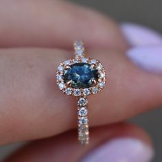 a woman's hand holding an engagement ring with a blue diamond