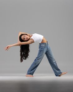 a woman is dancing in the air with her arms stretched out and hands behind her head