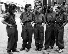 black and white photograph of four women in uniform talking to each other on the street