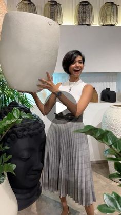 a woman standing next to a statue holding a large object in her hands and smiling