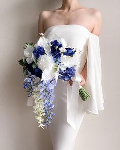 a woman in white dress holding a blue and white bouquet