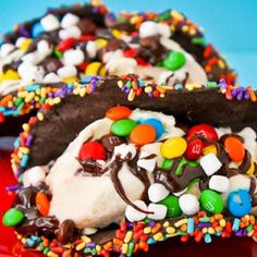 two pieces of chocolate covered ice cream with sprinkles and m & ms