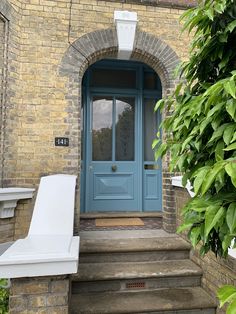 a blue front door with a white lawn chair sitting on the steps next to it