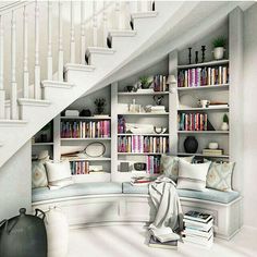 a living room filled with lots of furniture and bookshelves next to a stair case