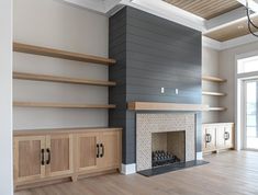 an empty living room with a fireplace and shelves