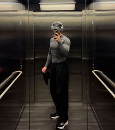 a man taking a selfie in front of an elevator with his cell phone to his ear