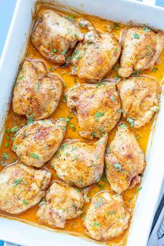 chicken thighs in a white casserole dish with parsley on the top, ready to be cooked