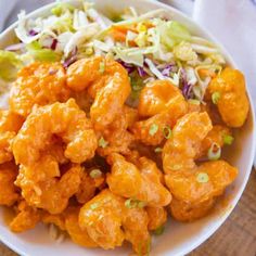 a white bowl filled with chicken and coleslaw next to slaw on a table