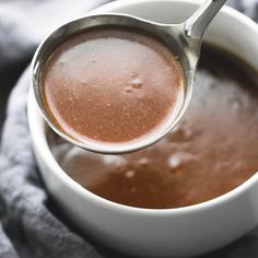 a spoon full of hot chocolate on top of a white cup filled with liquid and sugar