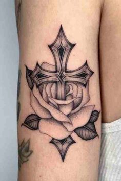 a cross and rose tattoo on the arm