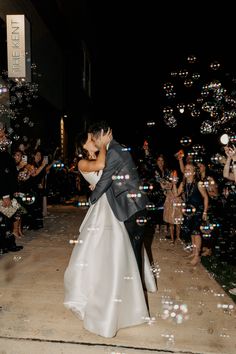 a bride and groom kissing in front of bubbles on the ground at their wedding reception