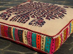 a colorful cushion with an elephant design on the front and back cover is sitting on a stone floor