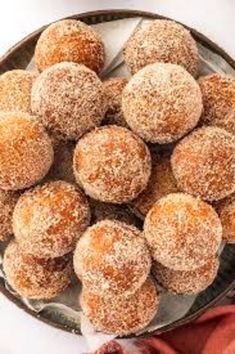 a plate filled with sugar covered donuts on top of a table