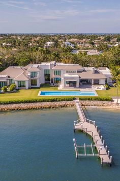 an aerial view of a house with a dock in the foreground and a swimming pool on the other side