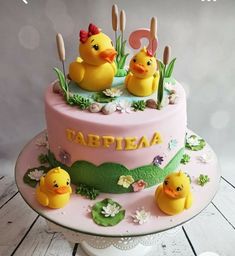 a pink cake with two rubber ducks on it