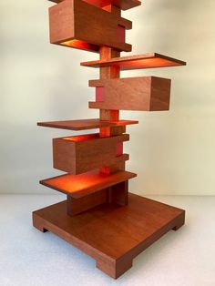 a tall wooden sculpture with red lights on it's sides and shelves in the middle